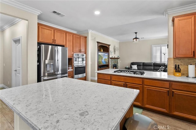 kitchen with ornamental molding, visible vents, backsplash, light wood-style floors, and stainless steel appliances