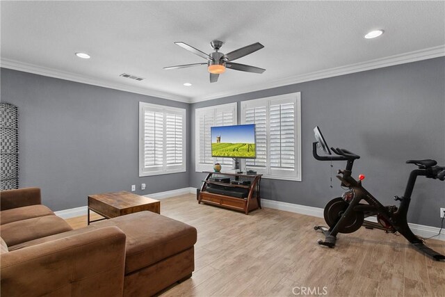 living area with crown molding, light wood-style floors, visible vents, and a ceiling fan