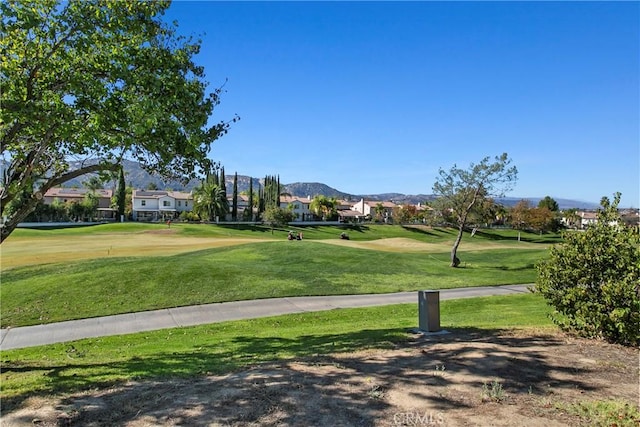 view of home's community featuring a mountain view, view of golf course, a residential view, and a lawn