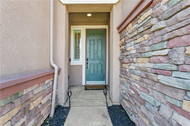 entrance to property with stone siding and stucco siding