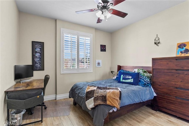 bedroom with wood finished floors, baseboards, ceiling fan, and an office area