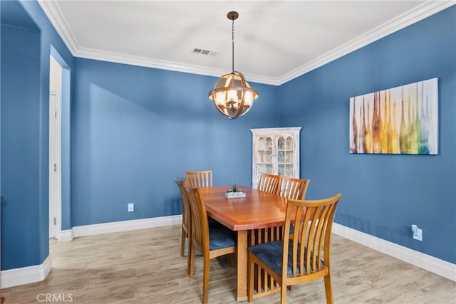 dining space with a chandelier, crown molding, visible vents, and wood finished floors