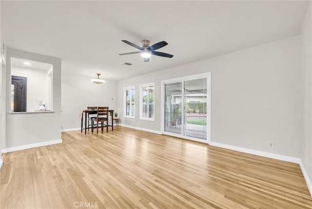 living area featuring baseboards, light wood-style floors, visible vents, and a ceiling fan