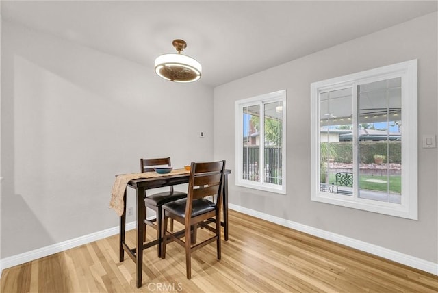 dining space featuring light wood-type flooring and baseboards