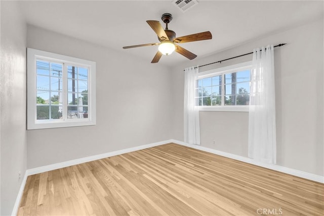 empty room with wood finished floors, visible vents, baseboards, and ceiling fan
