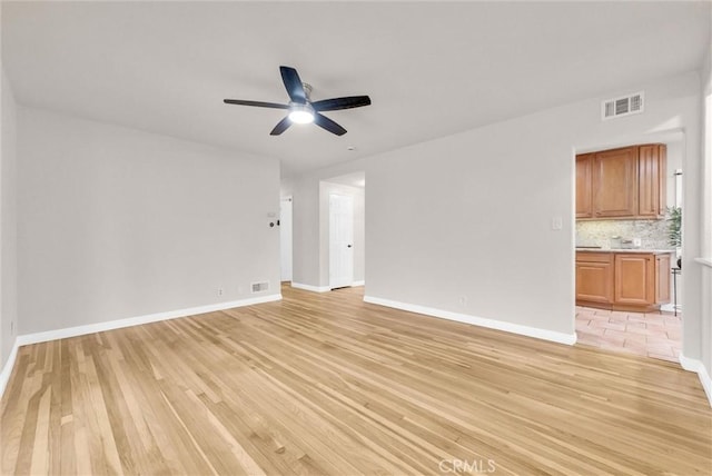 unfurnished living room with ceiling fan, baseboards, visible vents, and light wood-style floors