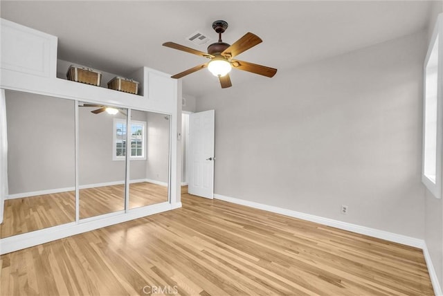 unfurnished bedroom with a closet, light wood-style floors, baseboards, and a ceiling fan