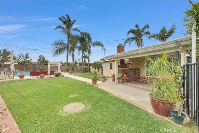 view of yard featuring a patio, an outdoor brick fireplace, a fenced in pool, and a fenced backyard