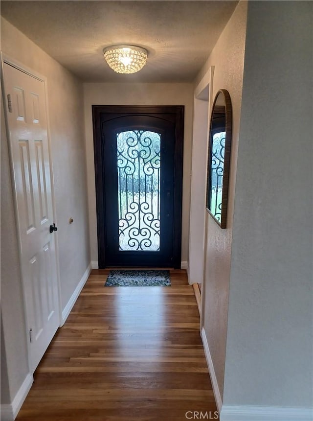 doorway to outside featuring baseboards, plenty of natural light, and wood finished floors