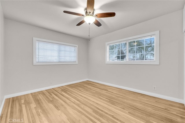 spare room with baseboards, light wood finished floors, and a ceiling fan