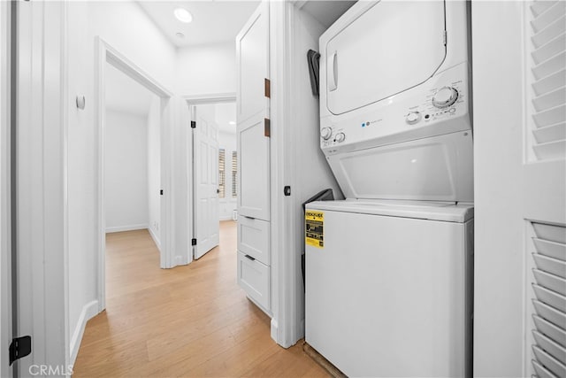 clothes washing area featuring stacked washer and clothes dryer, light wood-style floors, recessed lighting, and baseboards