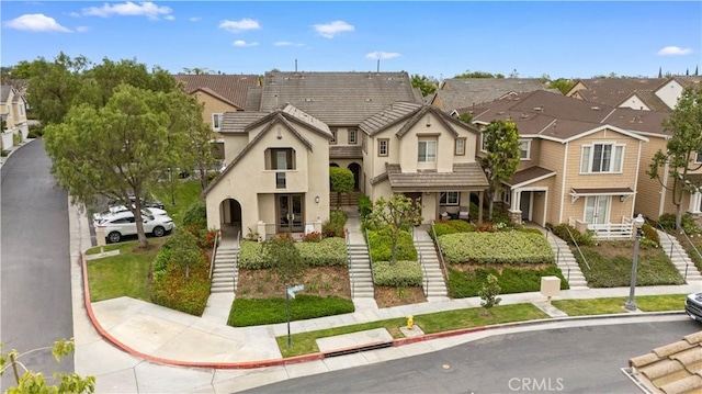 view of property with stucco siding, a residential view, stairway, and a tile roof