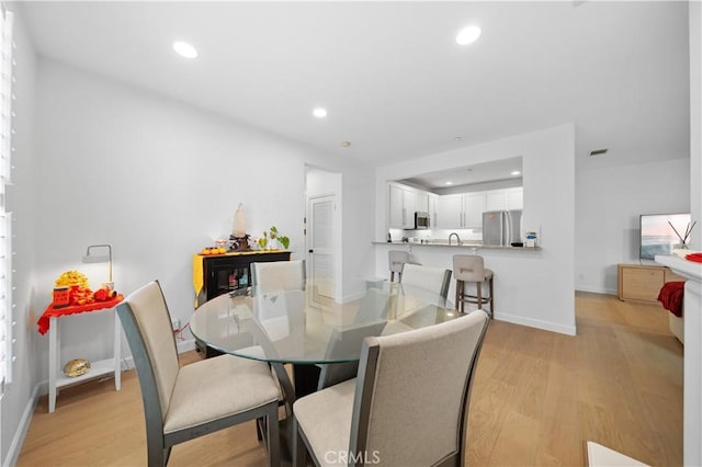 dining space featuring light wood-type flooring, recessed lighting, and baseboards