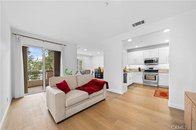 living area with light wood finished floors, baseboards, and recessed lighting