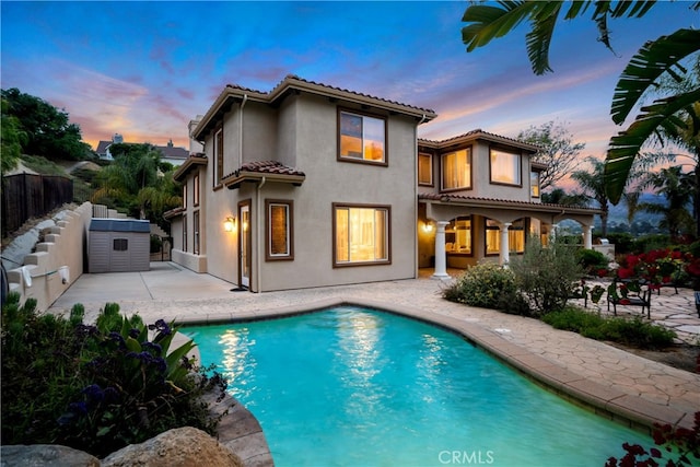 9420 Oak Leaf Dr, Chatsworth, CA 91311 - back of house at dusk featuring a fenced backyard, stucco siding, a patio area, and a tiled roof