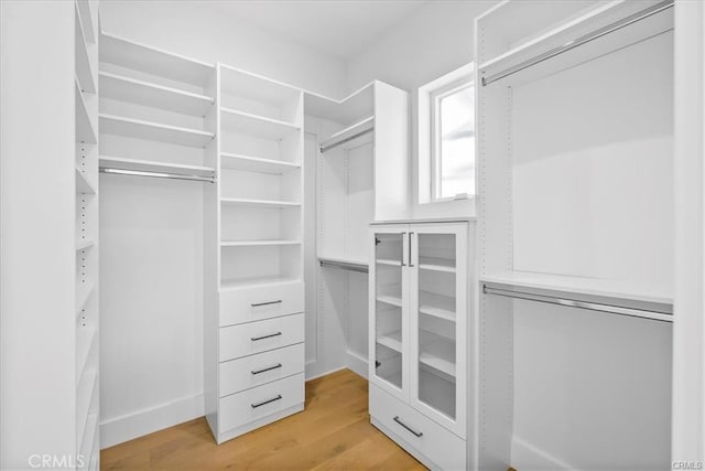 walk in closet with light wood finished floors