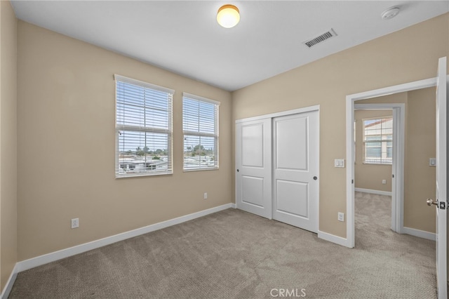 unfurnished bedroom with light colored carpet, baseboards, a closet, and visible vents