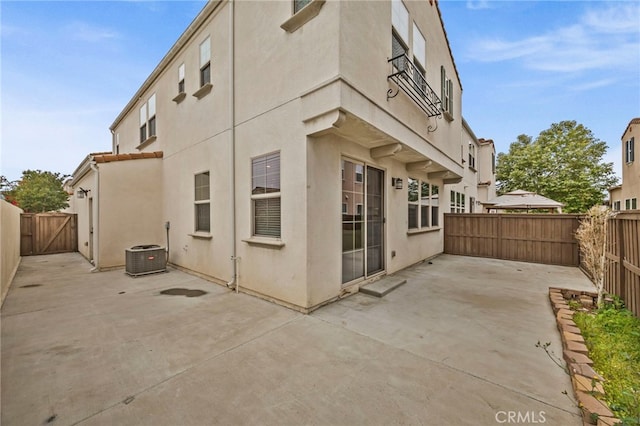 rear view of house with a fenced backyard, a patio, stucco siding, and central air condition unit