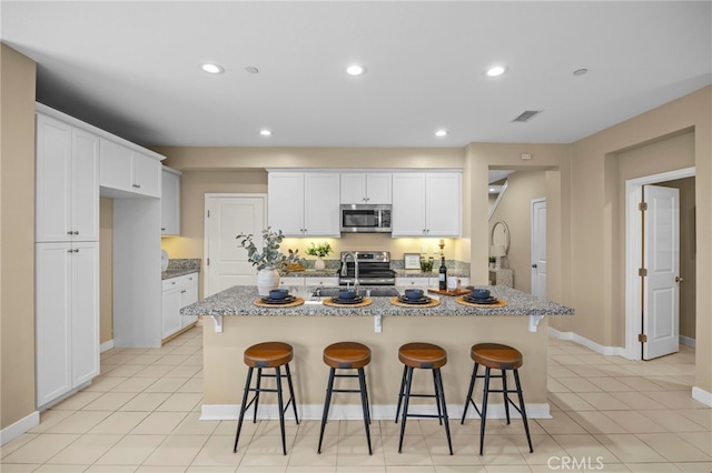 kitchen featuring appliances with stainless steel finishes, visible vents, a kitchen breakfast bar, and white cabinetry