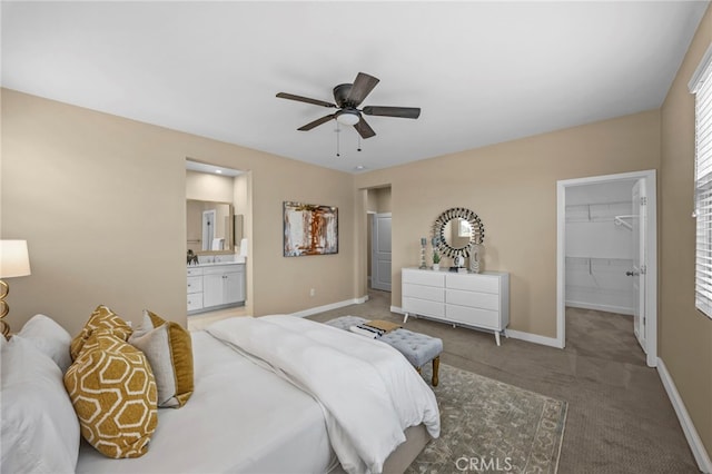 carpeted bedroom with a closet, a ceiling fan, a walk in closet, connected bathroom, and baseboards