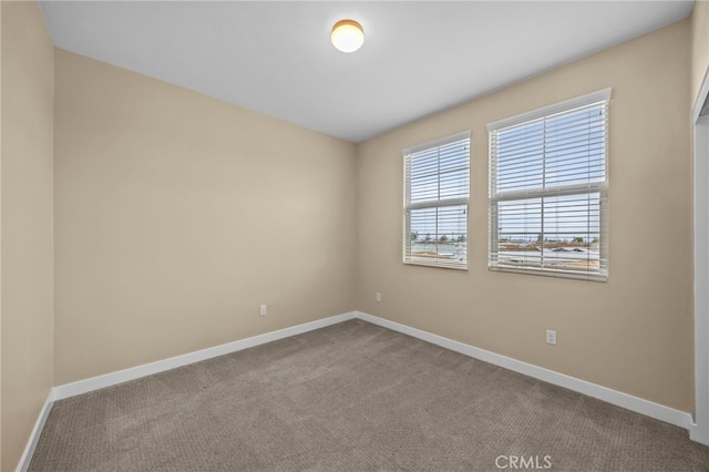 carpeted empty room featuring baseboards