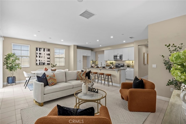 living room with light tile patterned floors, visible vents, baseboards, and recessed lighting