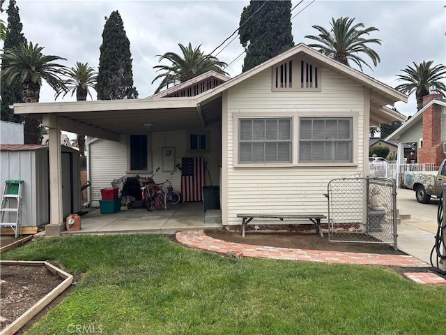 rear view of property with fence, a storage shed, an outdoor structure, a yard, and an attached carport