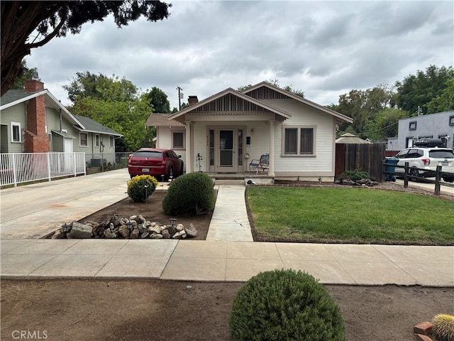 bungalow-style home with fence, a front lawn, and concrete driveway