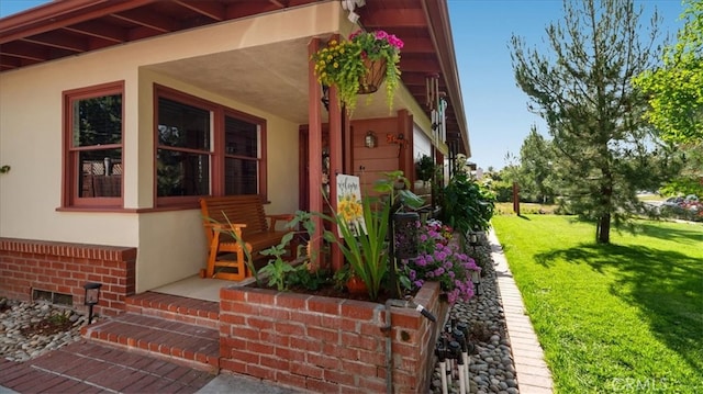 doorway to property featuring covered porch, stucco siding, and a yard