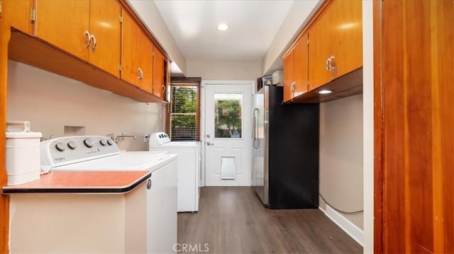 laundry area with cabinet space, dark wood finished floors, and washer and clothes dryer