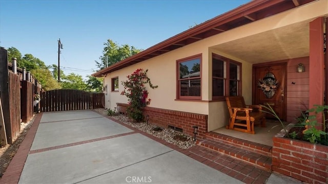 view of side of property with stucco siding, crawl space, fence, and a gate