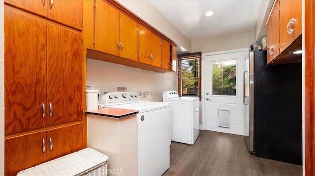 washroom featuring separate washer and dryer, cabinet space, and dark wood-type flooring