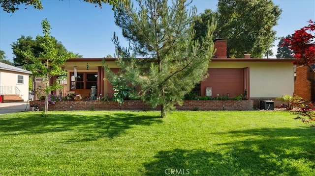 view of front of property featuring central AC unit, a chimney, and a front yard