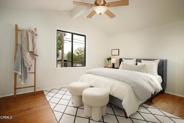 bedroom featuring baseboards, lofted ceiling with beams, light wood finished floors, and a ceiling fan