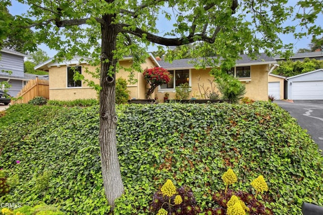 ranch-style home with aphalt driveway, fence, a garage, and stucco siding