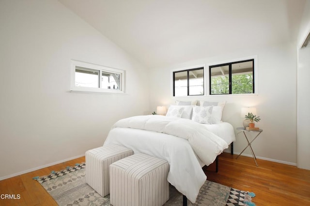 bedroom with multiple windows, wood finished floors, and lofted ceiling