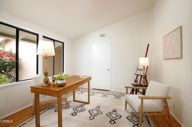 office with vaulted ceiling, baseboards, visible vents, and wood finished floors