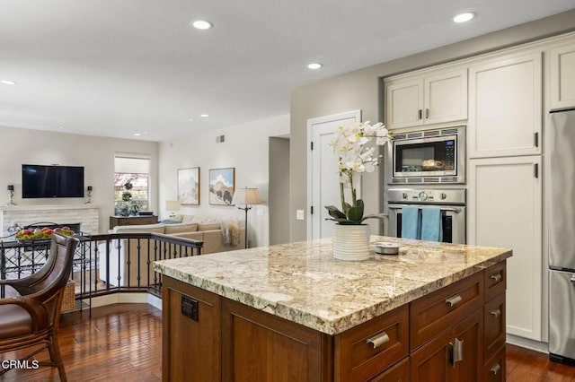 2113 Doral Ct, Oxnard, CA 93036 - kitchen featuring dark wood finished floors, white cabinets, light stone countertops, a kitchen island, and appliances with stainless steel finishes