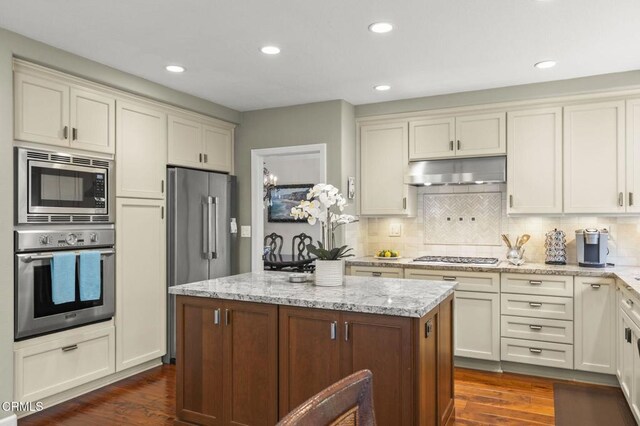 2113 Doral Ct, Oxnard, CA 93036 - kitchen featuring under cabinet range hood, stainless steel appliances, dark wood-type flooring, and light stone countertops