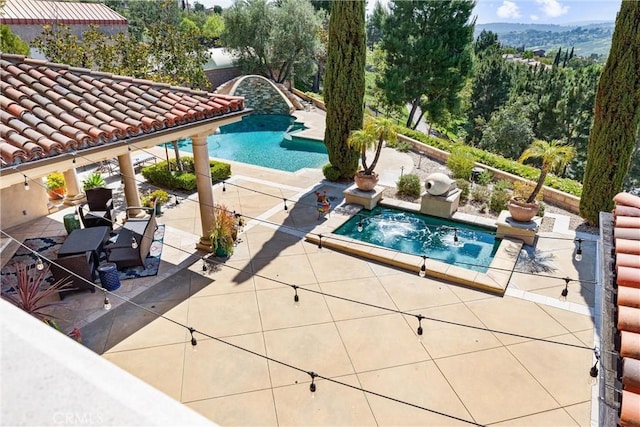 pool with a hot tub and a patio area