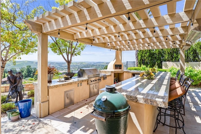 view of patio featuring a pergola, fence, outdoor wet bar, exterior kitchen, and grilling area