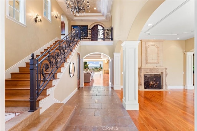 entryway with baseboards, crown molding, arched walkways, stairway, and ornate columns