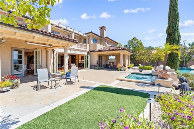back of property featuring stucco siding, a chimney, an outdoor pool, and a patio area