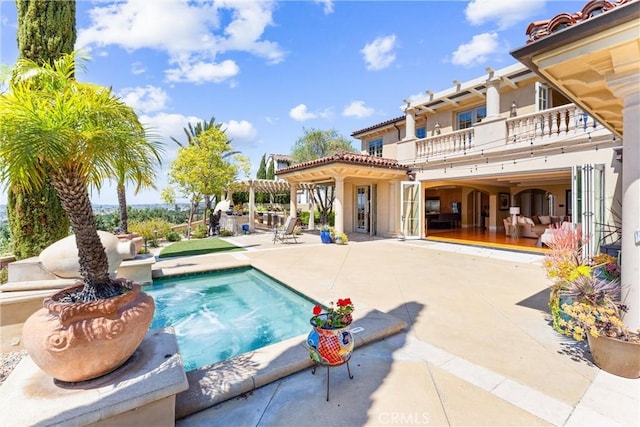 back of house featuring a patio area, stucco siding, an outdoor pool, and a balcony