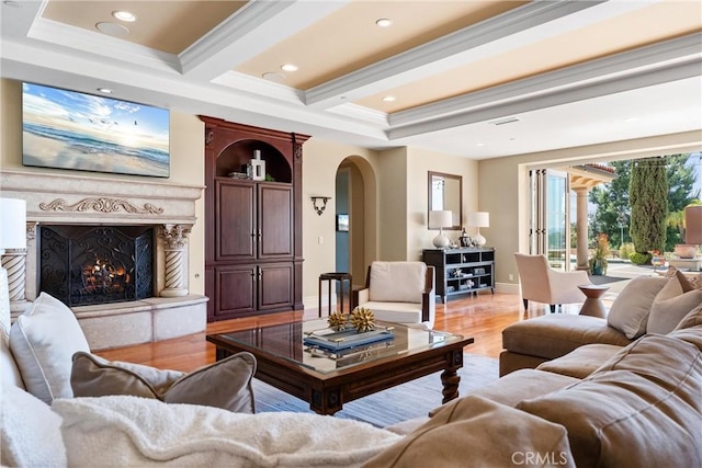 living room with arched walkways, light wood finished floors, a premium fireplace, and recessed lighting