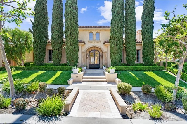 mediterranean / spanish-style house with a front lawn, stucco siding, and french doors