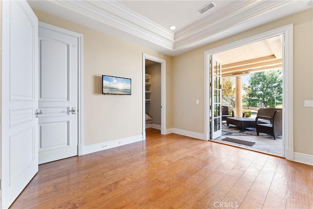 spare room with light wood finished floors, visible vents, baseboards, and ornamental molding