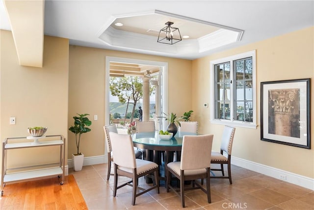 dining space featuring a tray ceiling, baseboards, and a healthy amount of sunlight