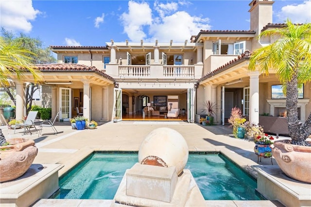 rear view of property featuring a balcony, a tile roof, a patio, stucco siding, and a pool