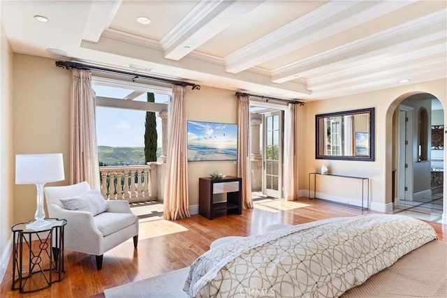 bedroom featuring baseboards, access to outside, crown molding, wood finished floors, and arched walkways